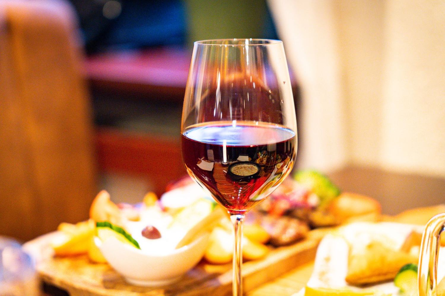 Glas Rotwein neben griechischen Vorspeisen
